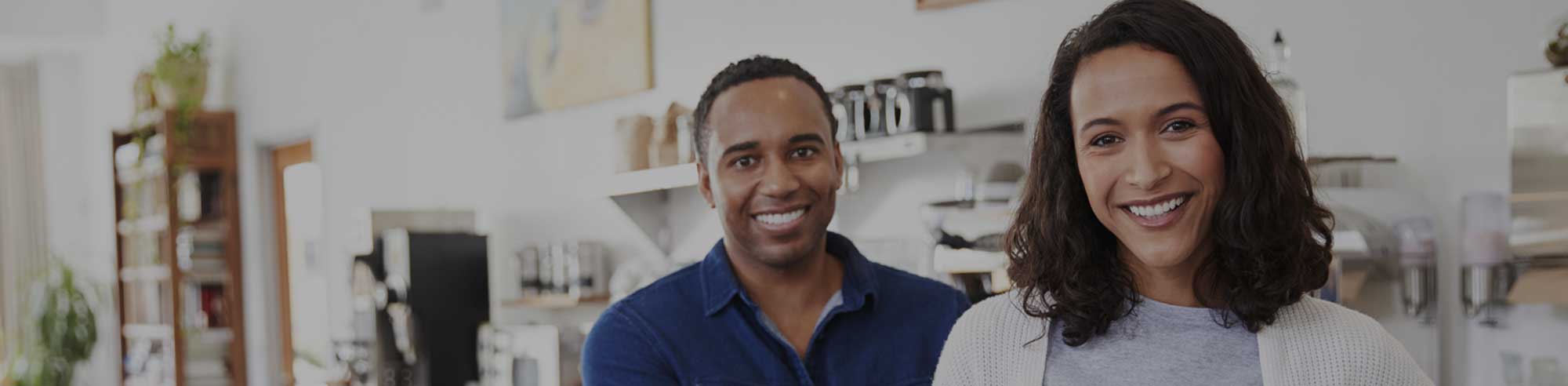 a man and woman smiling at the camera from their small business service counter